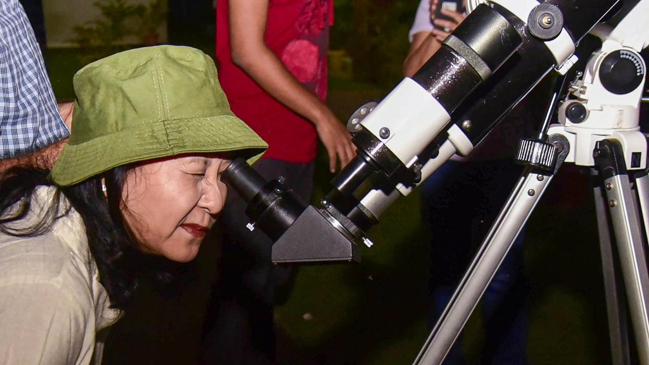 A woman looks through a telescope to watch the total Lunar Eclipse at Guwahati Planetarium on Tuesday. Pic/ PTI